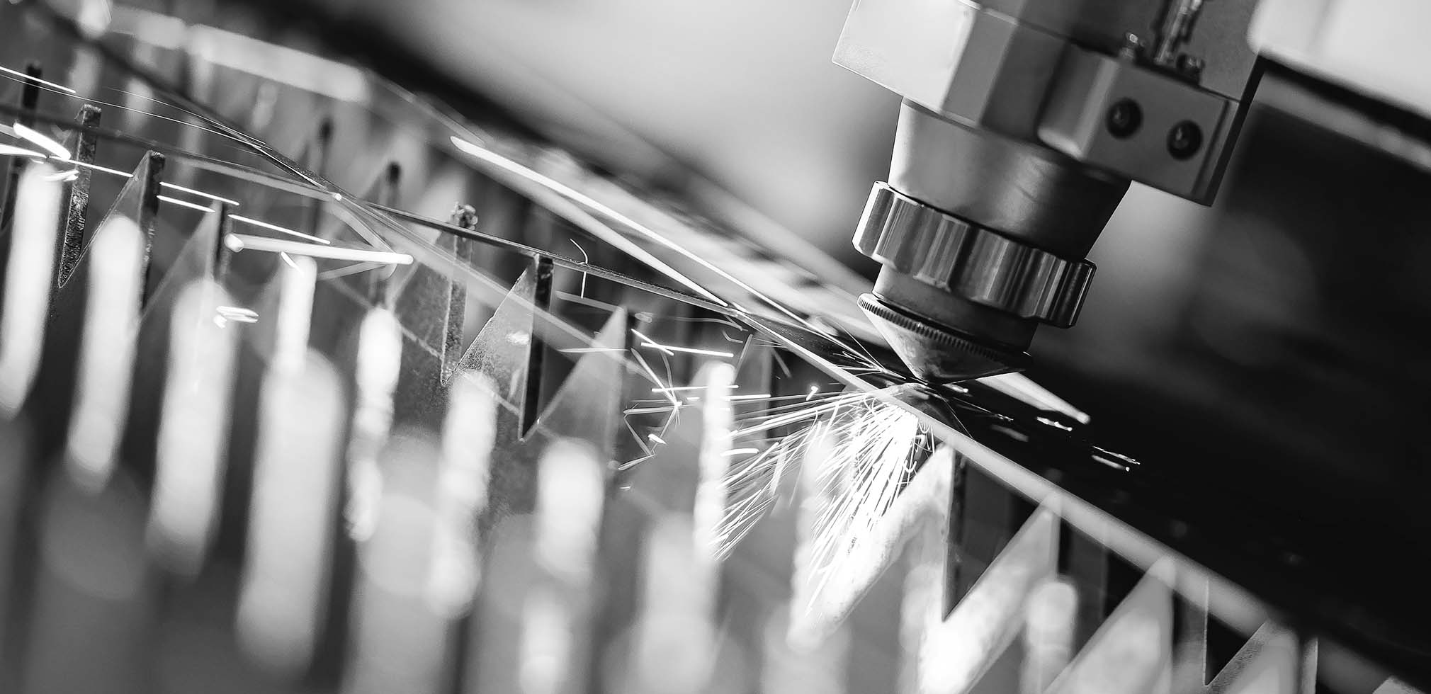 Black & White imagery Thin plastic sheet begin fed into a pressing cutting  machine via metal rollers with a reflection of the material in shiny metal  plate on factory cover. Stock Photo